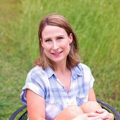 a woman sitting in a chair on the grass with her arms crossed and looking at the camera