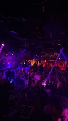 a crowd of people in a dark room with purple lights on the walls and floor