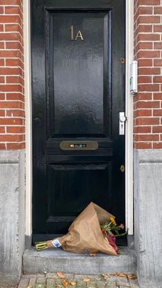 flowers and a brown paper bag sitting in front of a black door with the number 11 on it