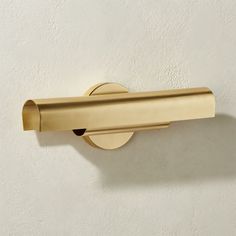 a gold toilet paper holder on a white wall