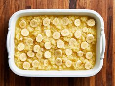 a casserole dish filled with bananas on top of a wooden table