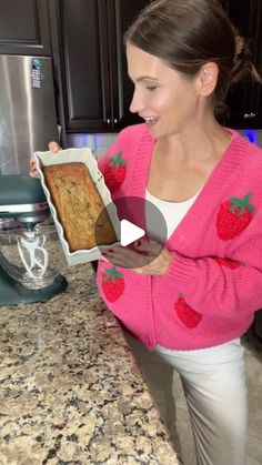 a woman is holding a box of baked goods