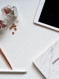 an ipad, pen, and other items on a white table with marbled paper