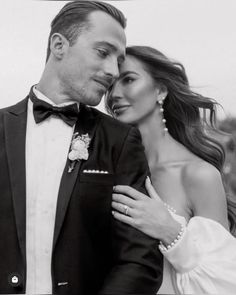 a man in a tuxedo and a woman in a dress pose for a black and white photo