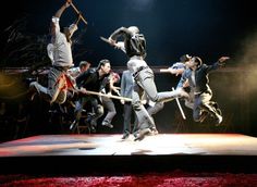 a group of people jumping in the air on top of a stage with one person holding a baseball bat