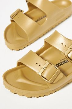 Rendered in a modern EVA finish, these sandals deliver a sporty update on the classic silhouette. You’re a shoe -in for incredible style and comfort when you slip on Birkenstock®. (P.S. it’s our favorite step when putting together an OOTD)! | Arizona EVA Sandals by Birkenstock in Gold, Women's, Size: 41 at Anthropologie Comfortable Gold Synthetic Sandals, Gold Synthetic Slides With Cushioned Footbed, Gold Synthetic Slides With Removable Insole, Casual Gold Synthetic Slides, Gold Casual Slip-on Slides, Trendy Slip-on Slides With Arch Support, Trendy Cushioned Sandals For Outdoor, Trendy Outdoor Sandals With Cushioned Footbed, Gold Leather Footbed Slides