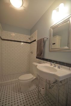 a white toilet sitting next to a sink in a bathroom under a mirror and lights