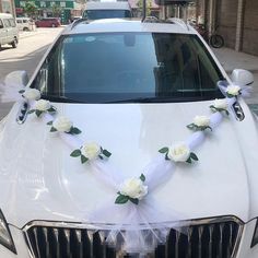 a white car decorated with flowers and ribbons