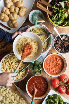 several bowls of pasta and vegetables on a table with utensils in each bowl