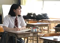 a woman sitting at a desk writing in a classroom