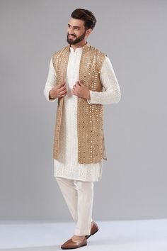 Gold open jacket with heavy mirror embroidery and a mandarin collar.
Components: 1
Pattern: Embroidered
Type Of Work: Mirror, Thread
Neckline: Mandarin collar
Sleeve Type: Sleeveless
Fabric: Georgette
Color: Gold
Other Details: 
Attached cotton lining
Note: Kurta and pant worn by the model is not for sale.
Occasion: Sangeet - Aza Fashions Luxury Men's Nehru Jacket With Suit Collar, Luxury Men's Nehru Jacket For Fall, Luxury White Nehru Jacket For Traditional Ceremonies, Luxury Men's Nehru Jacket For Festivals, Luxury Nehru Jacket With Mandarin Collar For Men, Festive Nehru Jacket With Gold Embroidery, Luxury Men's Nehru Jacket With Mandarin Collar, Formal Nehru Jacket With Gold Embroidery, Designer Gold Nehru Jacket With Embroidery