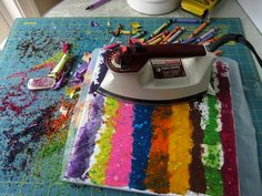 a table topped with lots of different colored crayons next to a white iron