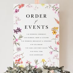 an order of events sign with flowers on it