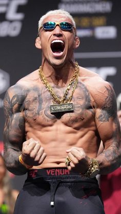 a man with tattoos on his chest and sunglasses in front of a crowd at a sporting event