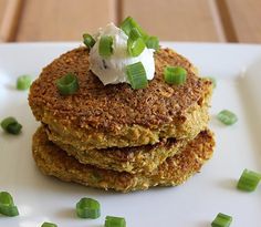 a stack of food sitting on top of a white plate covered in green onions and sour cream