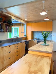 a kitchen with wooden cabinets and an island in the middle is lit by two pendant lights