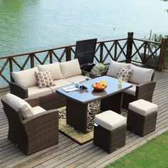 an outdoor patio furniture set on a wooden deck overlooking the water's edge with chairs and table