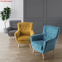 three different colored chairs sitting on top of a hard wood floor next to a potted plant