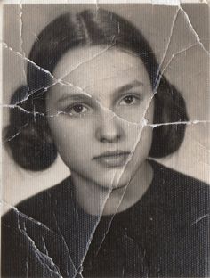 an old black and white photo of a woman's face through a cracked glass window