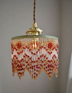 a chandelier hanging from a ceiling with red beads and gold chains on it