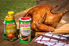 a whole chicken sitting on top of a wooden table next to two bottles of ketchup