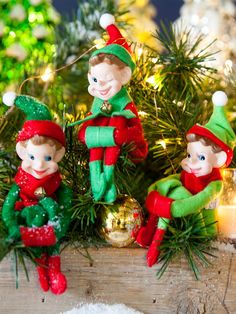 three elf figurines sitting on top of a christmas tree