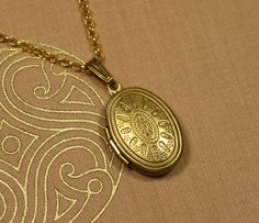 This pretty medallion pendant features a stylized sun on the front. The medallion is attached to a delicate pea chain that closes securely with a snap hook. The medallion can be opened from the side so that there is space inside for small memories that can always accompany you. -- Dimensions -- Length of chain 50 cm Medallion 24 x 14 mm -- MATERIAL -- The medallion chain is made of pure brass, an alloy of copper and zinc. Over time, the warm gold tone will acquire a patina that gives the piece o Gold Brass Amulet Locket Necklace, Gold Medallion Locket Necklace With Lobster Clasp, Gold Medallion Locket Necklace In Brass, Brass Locket Necklace With Adjustable Chain, Gold Medallion Necklace With Lobster Clasp, Gold Bohemian Locket Necklace With Antique Finish, Gold Brass Locket Necklace With Antique Finish, Antique Gold Brass Medallion Necklace As Gift, Antique Gold Brass Medallion Necklace Gift