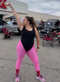 a woman in pink leggings holding up a red sign