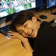 a young boy is laughing while using a computer keyboard and smiling with his hands on his face