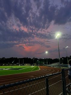 a person is standing on a track at night with the sun going down behind them