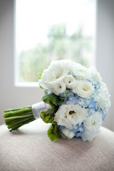 a bridal bouquet sitting on the back of a chair in front of a window