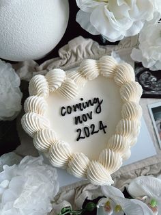 a heart shaped cake sitting on top of a table next to white flowers and photos