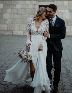 a man in a suit and tie standing next to a woman wearing a wedding dress