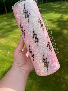 someone is holding up a pink glitter tumbler with black stars on it and the lid