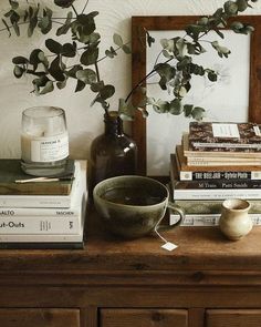 a table topped with books next to a vase filled with flowers and a candle on top of it