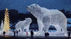 people are standing in front of an illuminated polar bear and cub