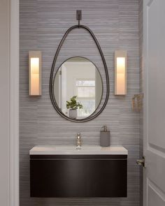 a bathroom with a sink, mirror and lights on the wall in front of it