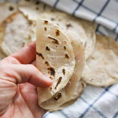 a hand is holding some tortillas on a towel