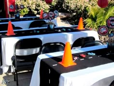 tables with white tablecloths and orange traffic cones on them are set up for an outdoor event