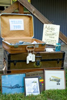 an open suitcase sitting on top of a grass covered field next to pictures and signs