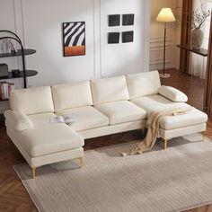 a living room with a white couch and ottoman on the floor next to a rug