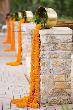 an orange flower garland is tied to the side of a brick wall with bells on it