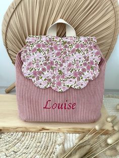 a pink purse sitting on top of a wooden table next to some knitting needles and yarn