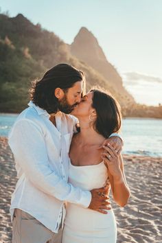 a man and woman kissing on the beach