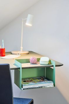 a desk with an open drawer on the top and a chair underneath it, in front of a white wall