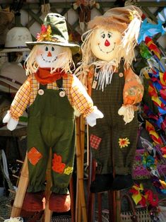 two scarecrows standing next to each other in front of hats and pumpkins