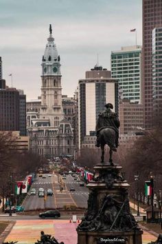 there is a statue in the middle of this street with many other buildings behind it