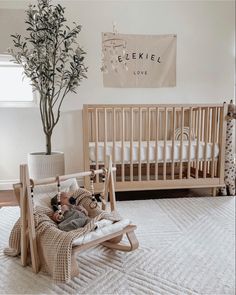 a baby's room with a crib, rocking chair and tree in the corner