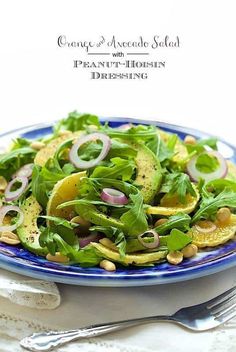 a blue and white plate filled with salad on top of a table next to silverware