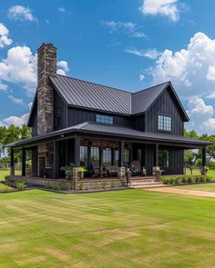 a large black house sitting on top of a lush green field